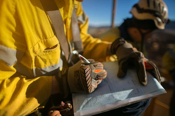 Construction miner supervisor wearing  safety glove signing working at height working permit on open field job site prior to starting high risk work each shift construction mine site Australia