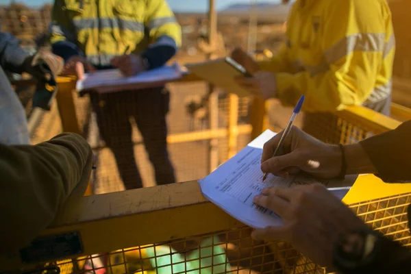 Safety workplace group of miner workers looking at personnel risk assessment take five book before written risk assessment prior to work of each task at construction mine site Perth, Australia