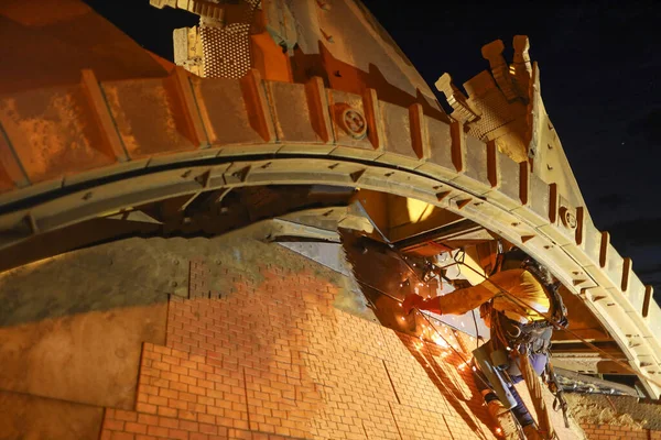 Rope access welder maintenance abseiler wearing fall safety body harness helmet protective equipment abseiling welding repairing reclaimer wheels bucket construction mine site Perth, Australia 