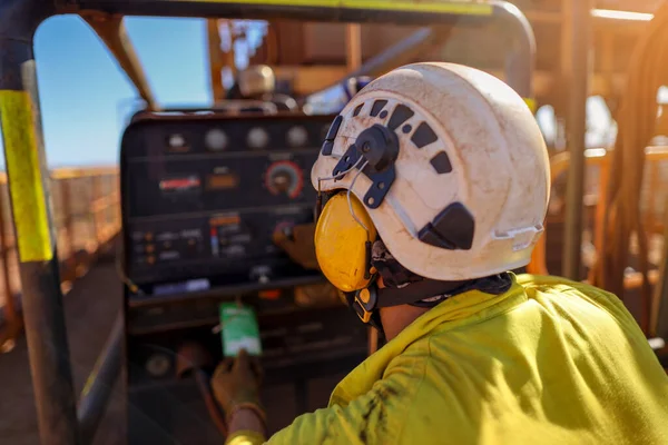 Safety workplace construction worker wearing side impact rope access safety white helmet attached with yellow noise disruptive earmuffs protection while inspecting working near generator prior performing work  mine site Australia 