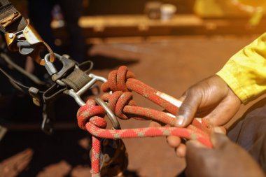 Safety first at work place rope access technician inspector conducting inspecting tension dressing barrel knot on locking Carabiner prior to commencing work abseiling working at heights harness. 