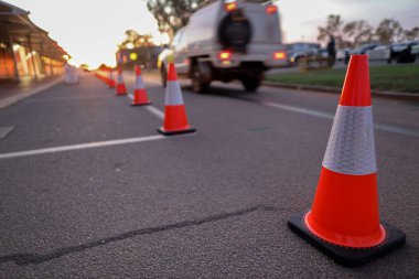 Red and white witches hat cone traffic warning signage barrier applying on busy street downtown on pedestrian footpath, road under construction at Karratha Airport, Pilbara region of Western Australia