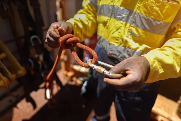 Safety first at work place rope access technician inspector conducting inspecting tension dressing barrel knot on locking Carabiner prior to commencing work abseiling working at heights harness. 