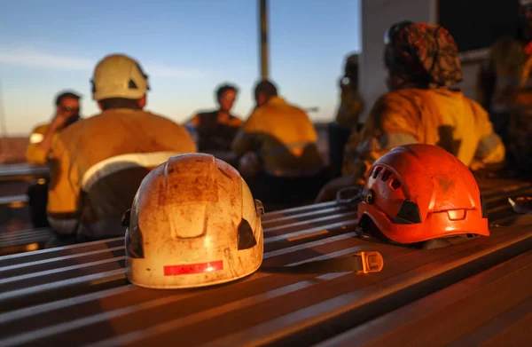 Colorful of Red rope access miner side impact safety helmet head fall protection place on the table with defocused miners at the background Perth, Australia