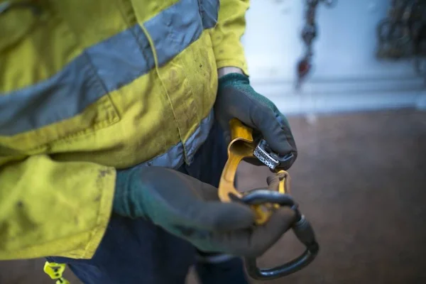 Safety first rope access technician inspector inspecting working at heights hand ascender safety equipment which connecting with locking carabiner prior to used on construction site, Perth Australia 