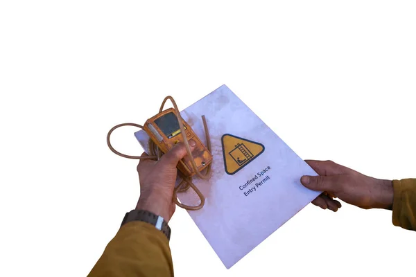 Safety work place certifies worker hands holding gas test detector atmosphere placing top of confined space permit book dropped shadow with isolated white background  
