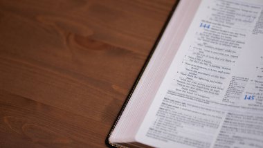 Bottom left corner of open Bible on a wooden background