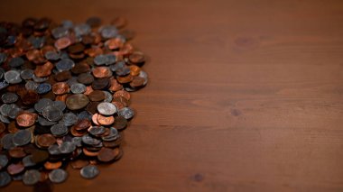 Top view of coin pile to the left of the screen on a wooden table