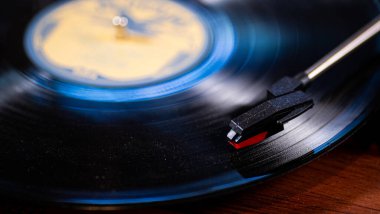 Vintage record with a blue hue playing on a turntable with a red needle