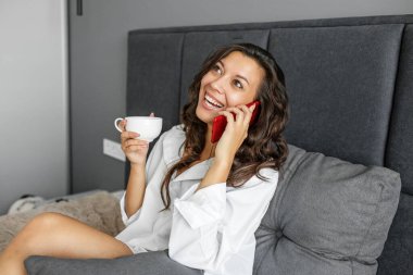Yatakta telefonda konuşan güzel bir kadın. Güzel bir iç mekan. Konuşan insanlar. Cep telefonu. Mobil bağlantı. Güzel iç mekan..