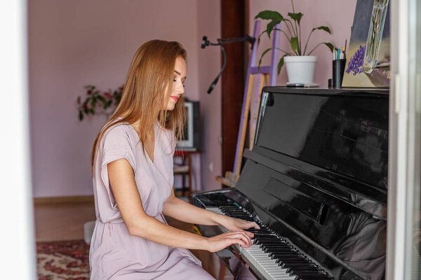 Молодая женщина играет дома на пианино. Пианист репетирует перед концертом. Хобби и развлечения. Любовь к классической музыке.