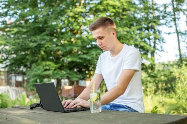 Dizüstü bilgisayarda çalışan bir adam, ahşap masadaki kır evinin bahçesinde gerçekten ilham verici bir yüze sahip.