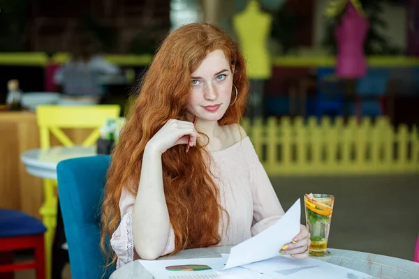 Yönetim ve pazarlama. Evrak işleri. Çok uzun kızıl saçlı. Öğrenci kafede materyal öğreniyor..