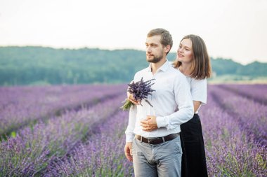 Güzel mutlu bir çift, mor lavanta tarlasında yürüyorlar, çiçek çayırında eğleniyorlar. Romantik randevu ve aşk