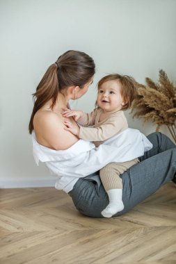 Little baby girl sits on mother's lap and smiles. Spend time together.