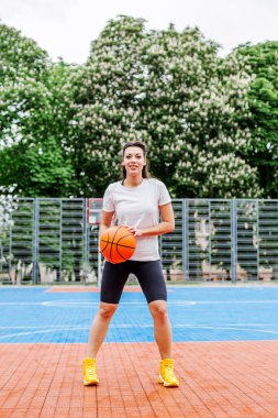 Spor anlayışı, hobiler ve sağlıklı yaşam tarzı. Genç atletik kadın, modern açık hava basketbol sahasında basketbol oynamak için antrenman yapıyor..