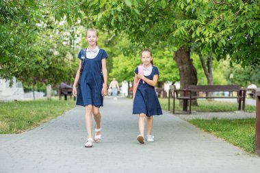 İki mutlu çocuk sırt çantalarıyla okula gider. Okula, öğrenmeye, arkadaşlığa ve çocukluğa geri dön..