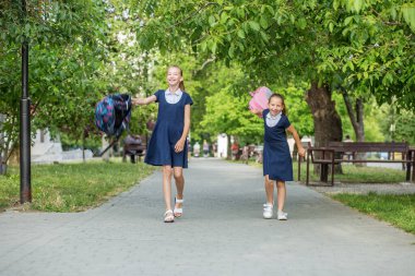 İki liseli kız okuldan ayrılıp sırt çantalarını fırlatıyorlar. Çocuklar eğleniyor. Okula, öğrenmeye, arkadaşlığa ve çocukluğa geri dön..