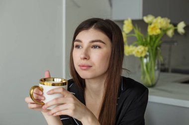 Sevimli genç esmer. Güzel siyah pijamalar. Sarı çiçekli güzel vazo. Samimi mutfak. Gri tonlarda modern iç mekan