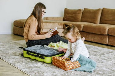Tatil hazırlığı. Genç kadın bebekle yolculuk için bavulunu hazırlıyor. Gerekli şeylerin defterinde listele.