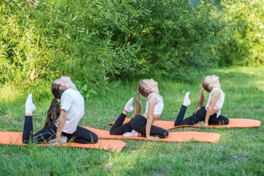 Group of children are doing exercises and stretching in nature using sports mats. Workout with gymnastics or aerobics or dance. Healthy lifestyle