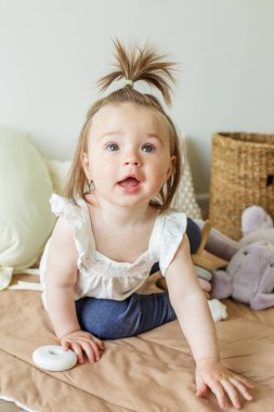 Toddler child plays with developmental toys. Little girl makes pyramid. Basket for toys. Cozy home. Happy baby