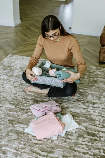 Young housewife sorts things and clothes and cleans house. Woman with eyeglasses. Organization of minimalist space.