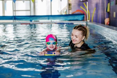 Swimming instructor teaches preschooler to swim in swimming pool. Hobby and leisure.