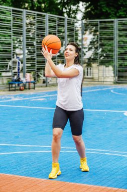 Spor anlayışı, hobiler ve sağlıklı yaşam tarzı. Genç atletik kadın, modern açık hava basketbol sahasında basketbol oynamak için antrenman yapıyor..