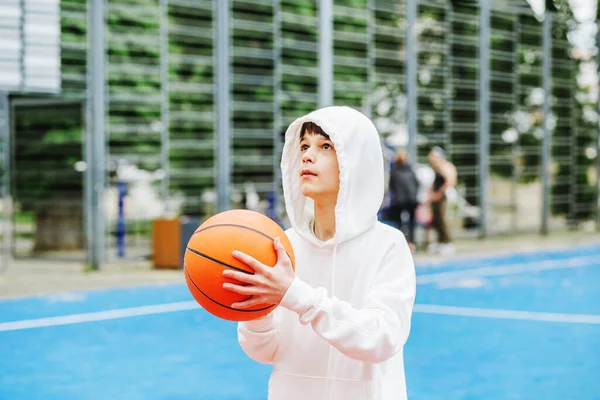 Concept of sports, hobbies and healthy lifestyle. Child schoolboy trains playing basketball on summer day.