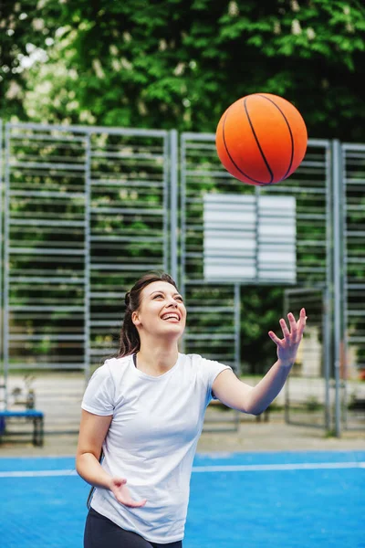 Spor anlayışı, hobiler ve sağlıklı yaşam tarzı. Genç atletik kadın, modern açık hava basketbol sahasında basketbol oynamak için antrenman yapıyor..