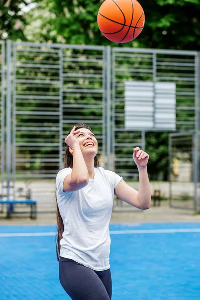 Spor anlayışı, hobiler ve sağlıklı yaşam tarzı. Genç atletik kadın, modern açık hava basketbol sahasında basketbol oynamak için antrenman yapıyor..