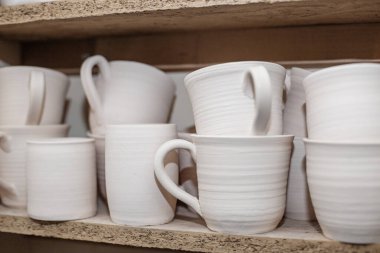 Wooden racks in pottery workshop, which have pottery, many different pottery items standing on shelves in pottery workshop