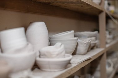 Wooden racks in pottery workshop, which have pottery, many different pottery items standing on shelves in pottery workshop