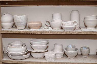 Wooden racks in pottery workshop, which have pottery, many different pottery items standing on shelves in pottery workshop