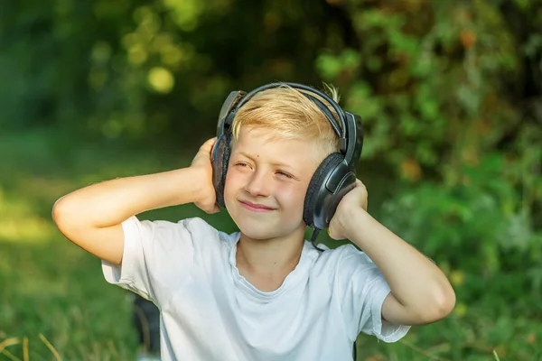 Preteen boy listening to song or audio book. Blond boy uses headphones. Concept of music, radio and songs, technology