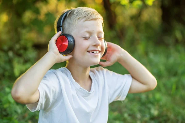 Preteen boy listening to song or audio book. Blond boy uses headphones. Concept of music, radio and songs, technology