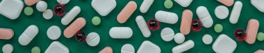 Many different pills on green background. Copy space. Top view. Concept of pharmaceuticals, medicine and healthcare. Banner for site