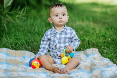 Beautiful joyful funny baby sitting on blanket. Toddler plays with toy. Concept of childhood, family and upbringing