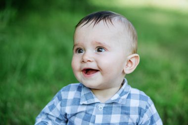 Portrait of little smiling boy in park. Close-up. Toddler boy walks in park. Brown eyes. Concept of childhood, family and upbringing