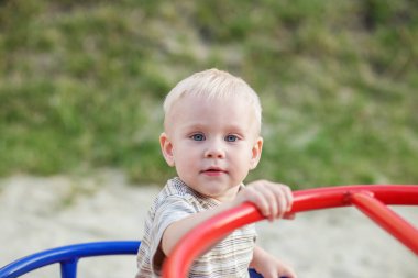 Küçük çocuk atlıkarıncada salıncak sürüyor. Bebekler yazın oyun bahçesinde oynarlar. Anaokulu, eğitim ve çocukluk kavramı.