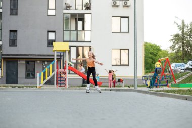 Güzel bir yaz günü parkta paten kaymayı öğrenen küçük bir kız. Etkin yaşam biçimi.