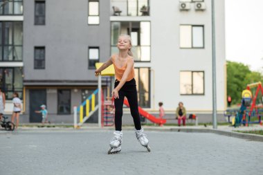 Güzel bir yaz günü parkta paten kaymayı öğrenen küçük bir kız. Etkin yaşam biçimi.