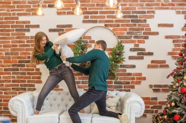 Beyaz kanepe. Aile kavramı, Noel ve kış mevsimi. Çiftler eğleniyor ve odada yastık savaşı yapıyor. Noel dekoru.