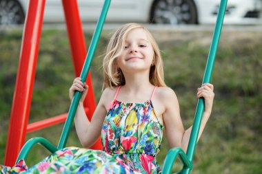 Çocuk kız çocuk parkında salıncakta sallanıyor. Çocukluk, eğlence ve eğlence konsepti.