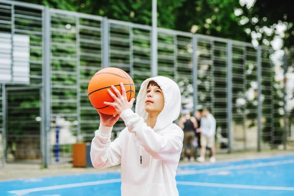 Concept of sports, hobbies and healthy lifestyle. Child schoolboy trains playing basketball on summer day.