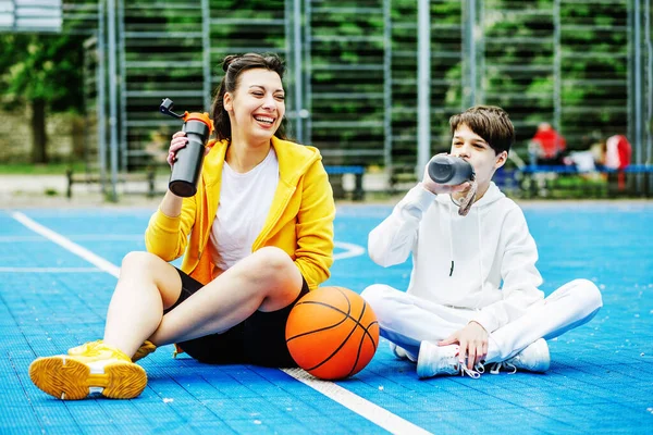 Genç Erkek Kız Spor Sahasında Oturuyorlar Içiyorlar Teneffüste Dinleniyorlar Basketbol — Stok fotoğraf