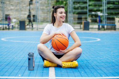 Yeniden kullanılabilir su şişesi. Bayan sporcu basketbol sahasında dinleniyor, su içiyor. Spor ve hobi kavramı.