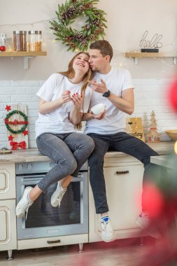 Birbirini seven çiftler, sabahları mutfakta oturup kahve içiyorlar. Aile kavramı, sevgi, rahat ev ve Noel