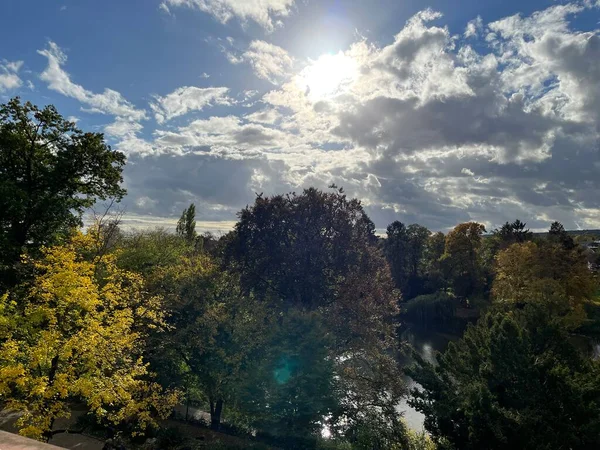 Mavi ve güneşli bulutlu gökyüzü ile tepedeki ağaçlar